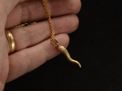 thumbnail of Vintage textured gold Italian cornicello charm on chain, held in hand.