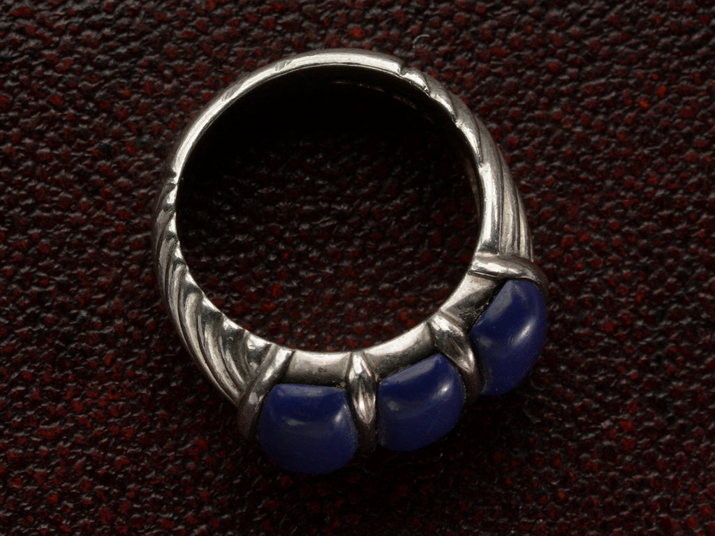 The side profile of a silver ring featuring three polished dark blue resin stones, shown against dark textured background