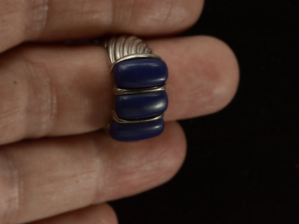 A silver ring featuring three polished dark blue resin stones, shown worn on a finger