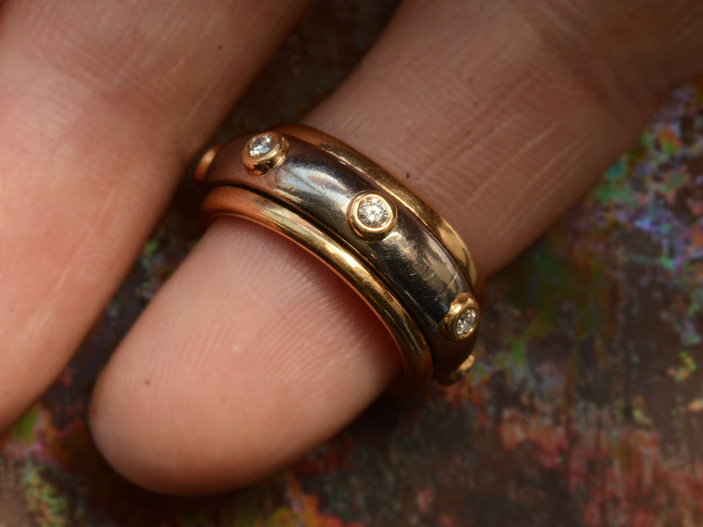 Front view of a vintage two-toned yellow and white gold diamond eternity band with a spinning mechanism. Shown on hand.