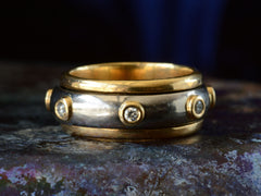 thumbnail of Front view of a vintage two-toned yellow and white gold diamond eternity band with a spinning mechanism. Shown on dark background.