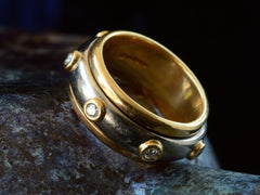 thumbnail of Angled front view of a vintage two-toned yellow and white gold diamond eternity band with a spinning mechanism. Shown on dark background.