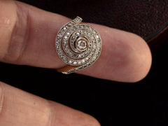 thumbnail of A vintage spiral form ring with diamonds in a white gold topped yellow gold mounting, shown on finger.