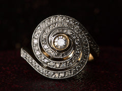 thumbnail of Face on view of a vintage spiral form ring with diamonds in a white gold topped yellow gold mounting, shown on dark background.