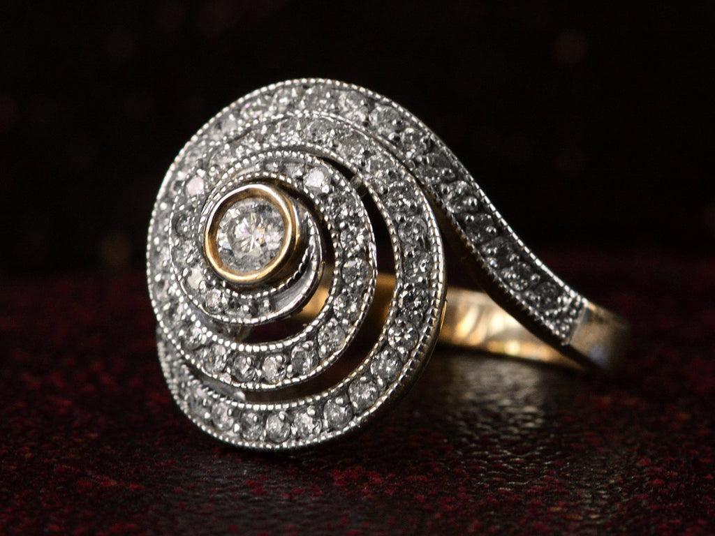 Right side view of a vintage spiral form ring with diamonds in a white gold topped yellow gold mounting, shown on dark background.