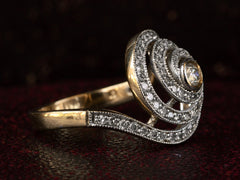 thumbnail of Left side view of a vintage spiral form ring with diamonds in a white gold topped yellow gold mounting, shown on dark background.