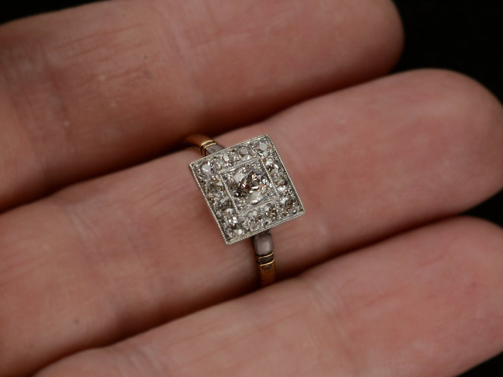 An antique platinum topped yellow gold square cluster ring with old cut diamonds, shown on finger