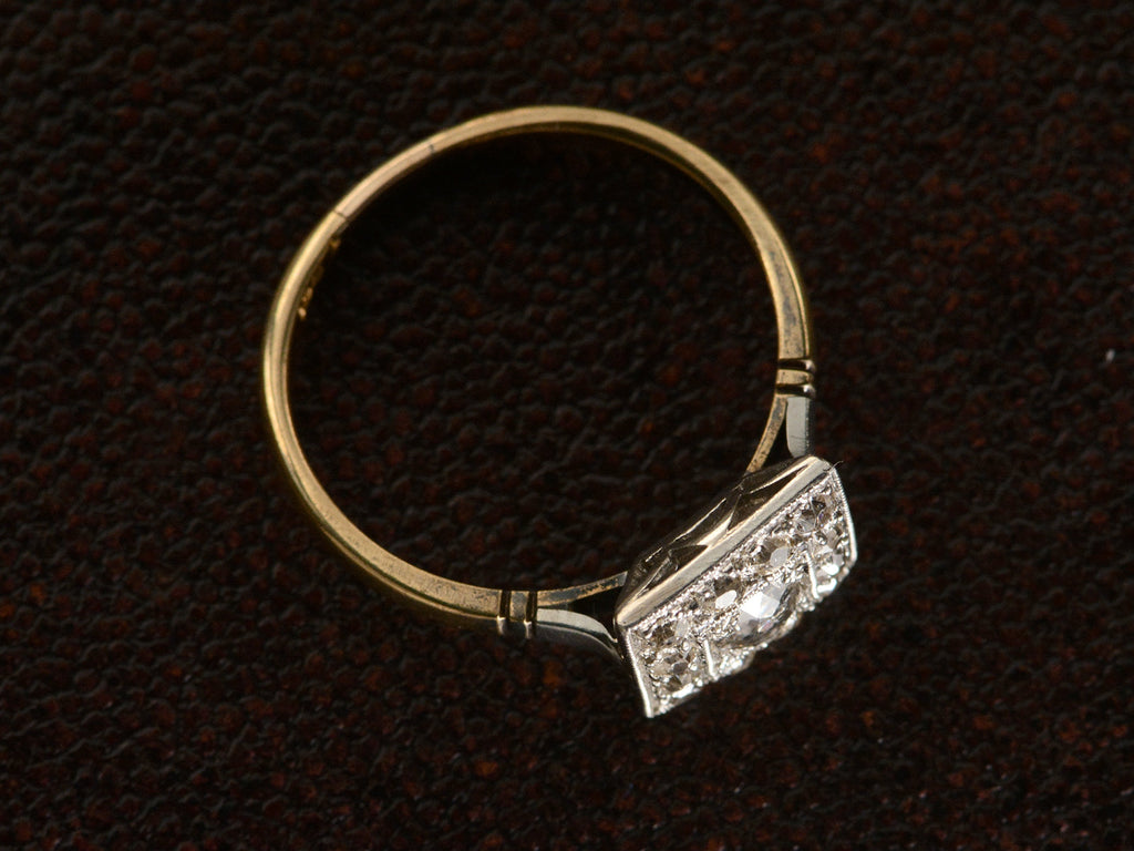 Angled view of antique platinum topped yellow gold square cluster ring with old cut diamonds, shown on dark textured background.