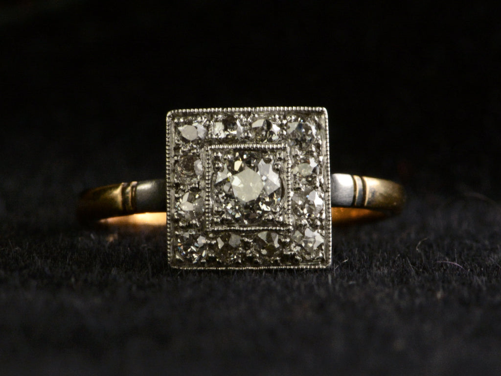 Front view of antique platinum topped yellow gold square cluster ring with old cut diamonds, shown on dark background.
