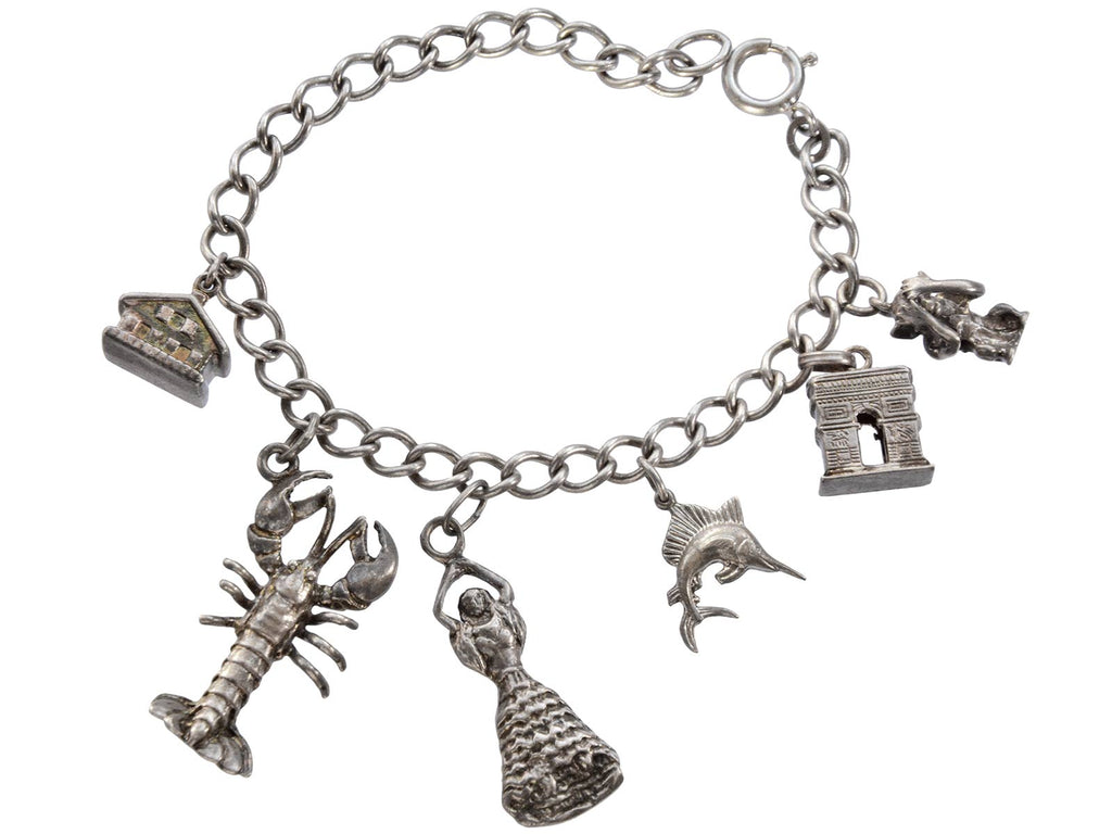 Vintage Silver Charm Bracelet showing a house, a lobster, a dancer, a fish, the Arc de Triomphe and a monkey. On a white background.