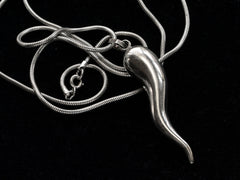 thumbnail of Detail of a vintage Italian silver necklace with a large cornicello horn pendant on a snake chain, shown on black background