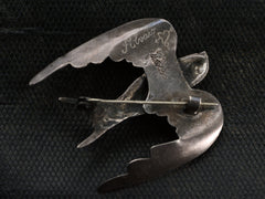 thumbnail of Reverse side of sterling silver dove brooch on dark textured background. Stamped "MEXICO" and signed "Alvaro" with a heart and arrow symbol.