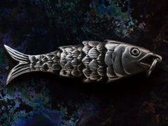 thumbnail of A right facing sterling silver articulated fish pendant on dark iridescent background.