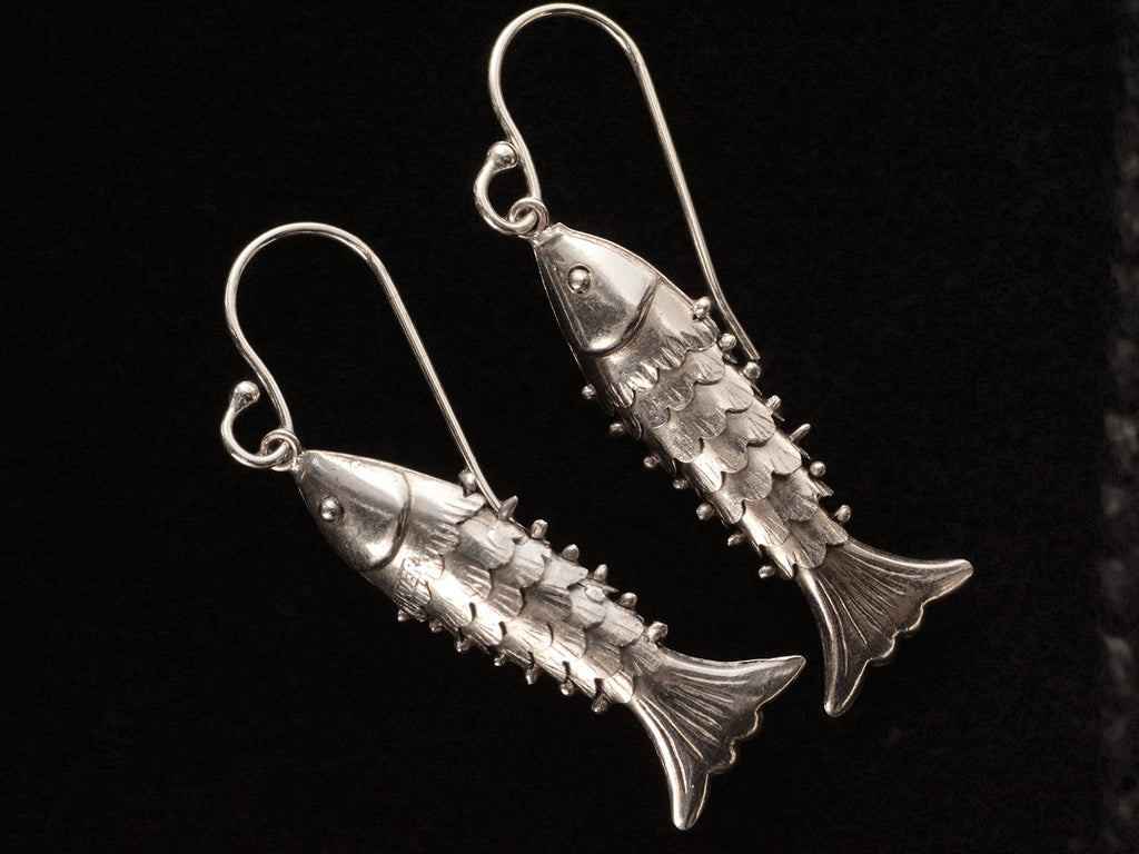 Silver articulated fish earrings, on black background