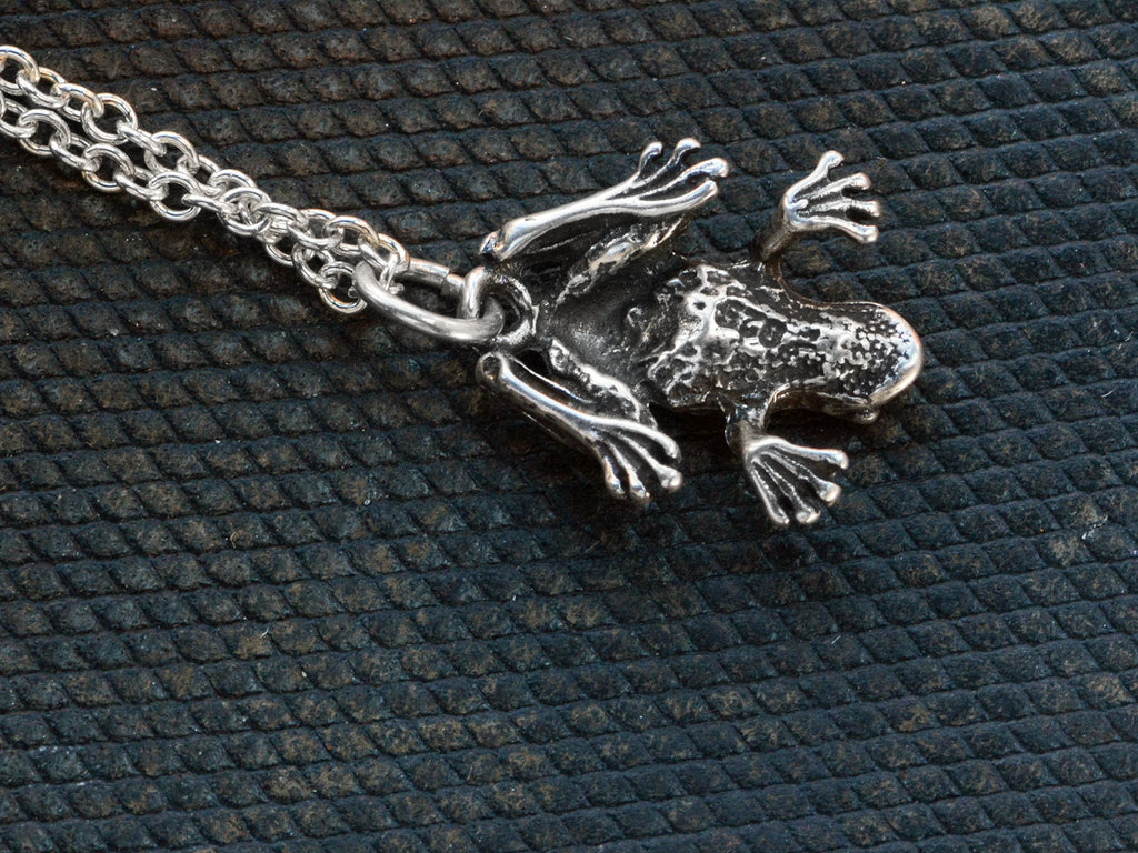 Reverse side of a vintage sterling silver frog pendant on chain, shown on dark textured background. "925" stamp visible