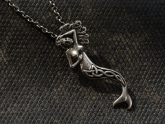 thumbnail of Detail of vintage silver mermaid pendant with Celtic design on tail, shown hanging from cable chain on dark textured background