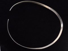 thumbnail of Reverse side of a simple silver neck cuff shown on black background.