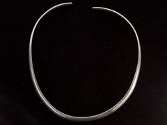 thumbnail of A simple silver neck cuff shown on black background.