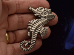 thumbnail of Front side of large vintage c1950 sterling silver seahorse brooch on hand.