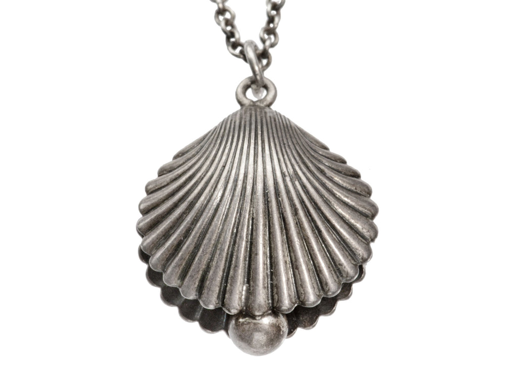 Antique silver shell pendant on a chain against a white background