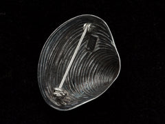 thumbnail of Reverse view of silver ribbed clam shell brooch showing pin fittings and a maker's mark that reads "BEAU STERLING". On black background.