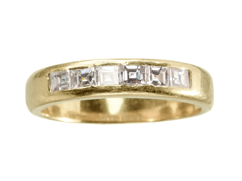A vintage yellow gold band channel-set with six rectangular step cut diamonds, shown on white background