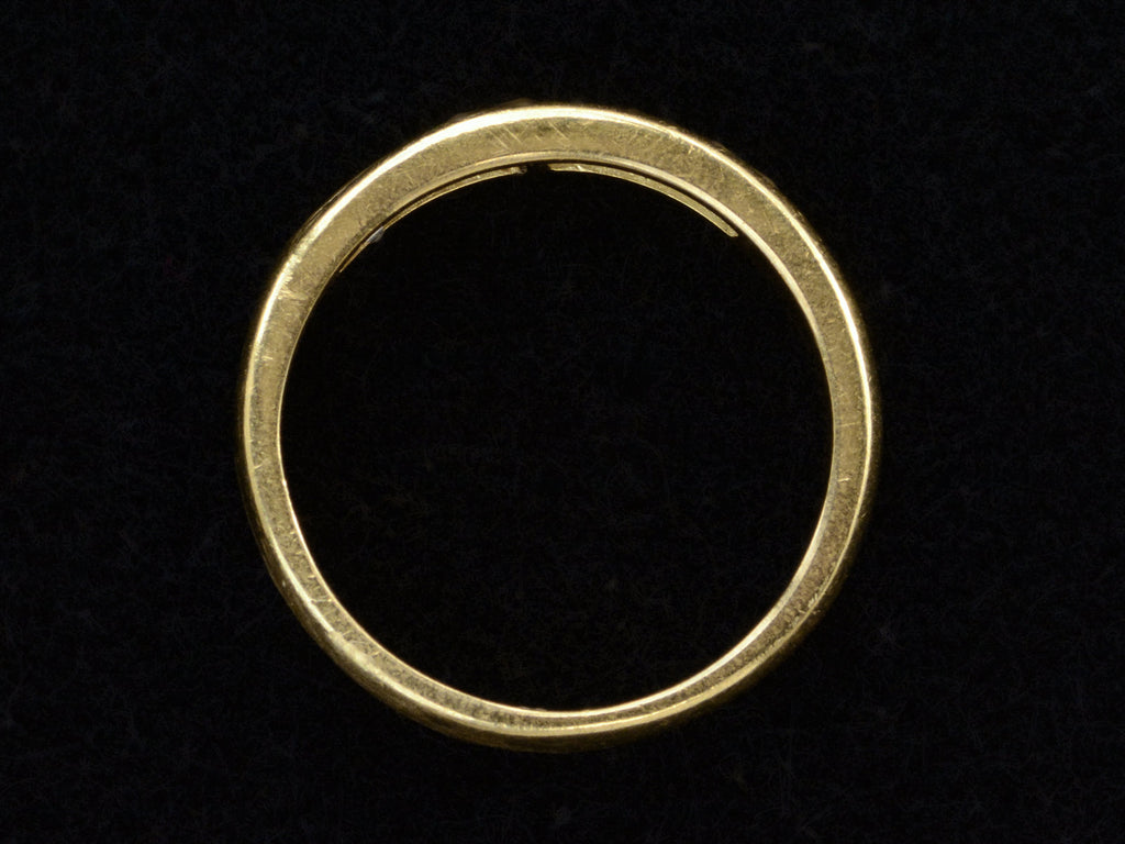 Side profile of a vintage yellow gold band channel-set with six rectangular step cut diamonds, shown on black background