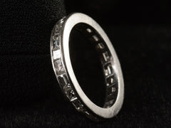 thumbnail of Angled view of platinum eternity band set with square and rectangular diamonds, shown on black background.