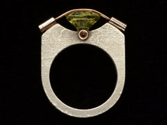 thumbnail of Side profile of Plodowski ring with a green stone tension set with yellow gold against a silver mounting, shown on black
