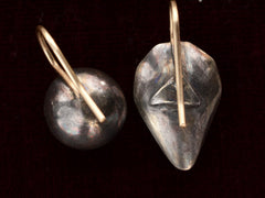 thumbnail of Backside view of mismatched earrings made from pink foiled silver set buttons on gold ear wires. On black background.