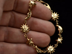 thumbnail of A yellow gold bracelet with figural links depicting suns, stars and moons, on hand.
