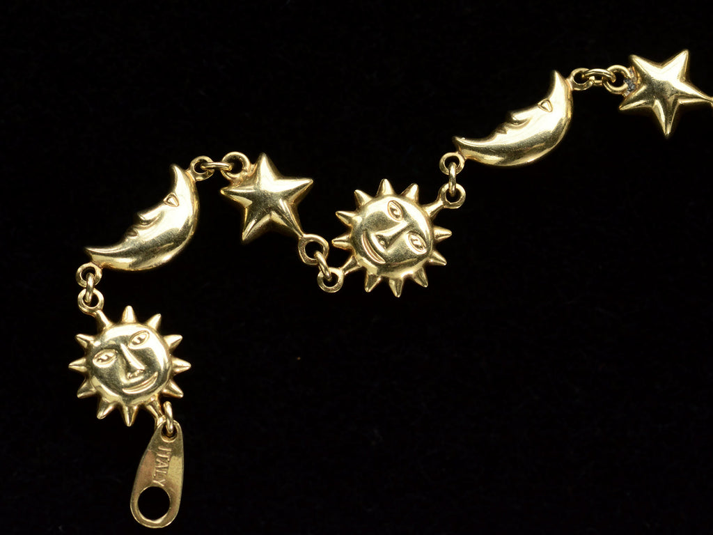 Detail view of yellow gold bracelet with figural links depicting suns, stars and moons, on dark background. An "ITALY" stamp is visible.