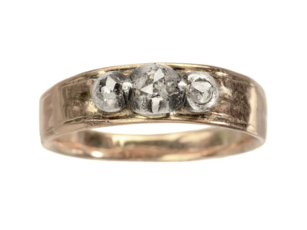 An antique rose gold and silver ring with three rose cut diamonds. Shown on white background.
