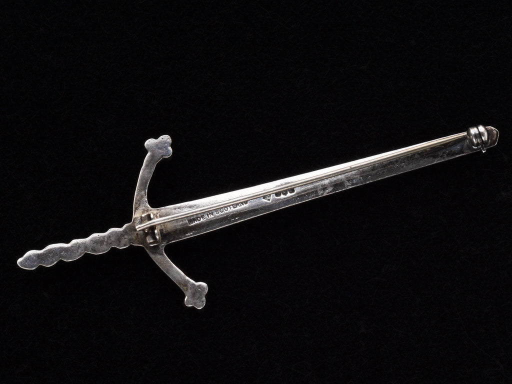 Reverse side of large silver sword brooch showing tiny hallmarks and "MADE IN SCOTLAND" stamp.
