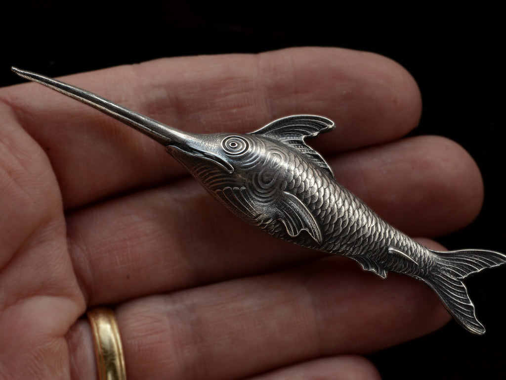 Antique silver sewing stiletto in the form of a swordfish, shown held in hand