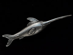 thumbnail of Backside of antique silver sewing stiletto in the form of a swordfish, shown on black background. Stamps visible reading "STERLING" and "2179"