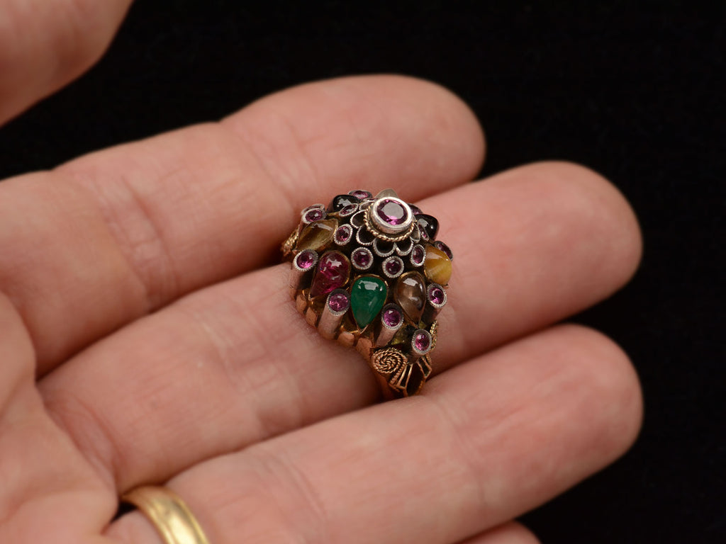 Tall tiered vintage ring set with rubies, and colorful gemstones in silver and gold. On finger
