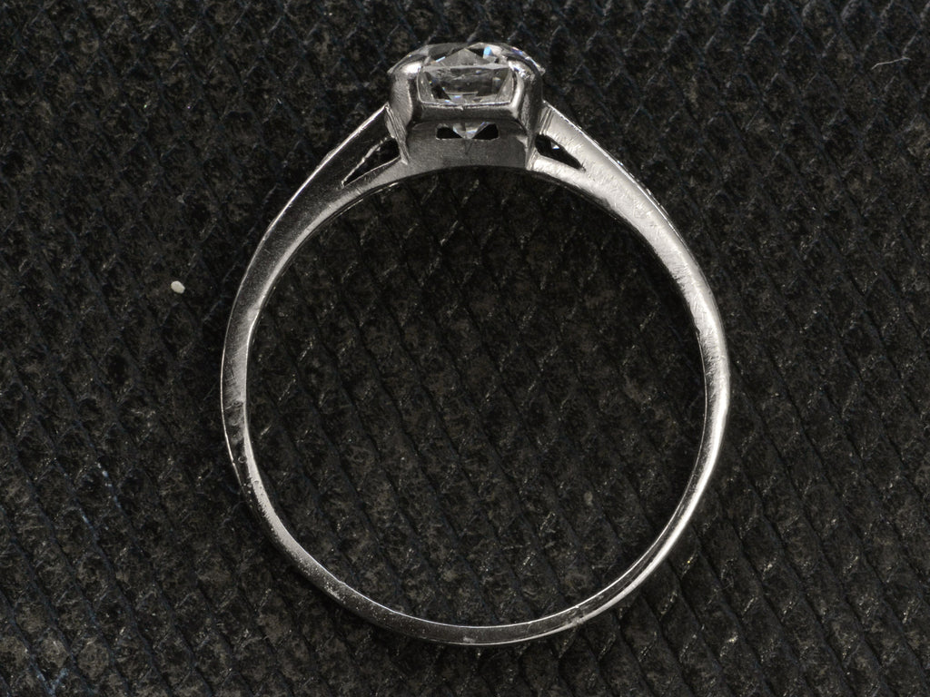 Side profile of a c1930 Art Deco Tiffany & Co platinum engagement ring shown on dark textured background.