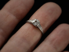 thumbnail of A c1930 Art Deco Tiffany & Co platinum engagement ring with a round old cut diamond and three smaller diamonds on each shoulder, tapering in size shown on finger.