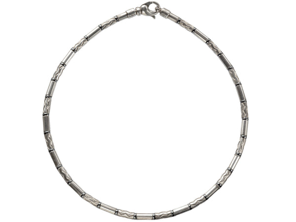 A vintage Tiffany "Aztec" necklace with barrel-shaped sterling silver beads interspersed with narrow bands of hematite and alternating with zig-zag embellished beads, shown on white background.