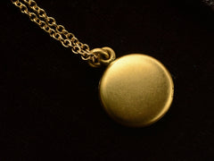 thumbnail of Small  gold round antique locket on chain, on black background.