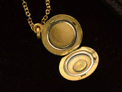 thumbnail of Small  gold round antique locket on chain, on black background, shown open. A stamp inside says "1/4 GOLD CASED"