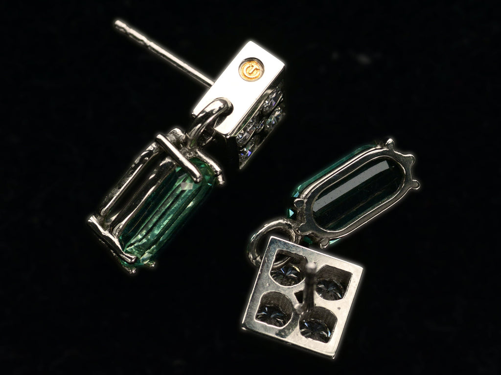 Side profile and back view of c1990 white gold earrings with diamond-shaped diamond studded tops and teal tourmaline pendants (on black background). A yellow gold makers mark is visible with the letters U and T