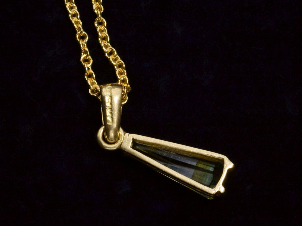 Backside detail of c1980 Green and White Tourmaline Pendant in Yellow Gold. Indecipherable stamp visible on the back of the bale. On dark background.