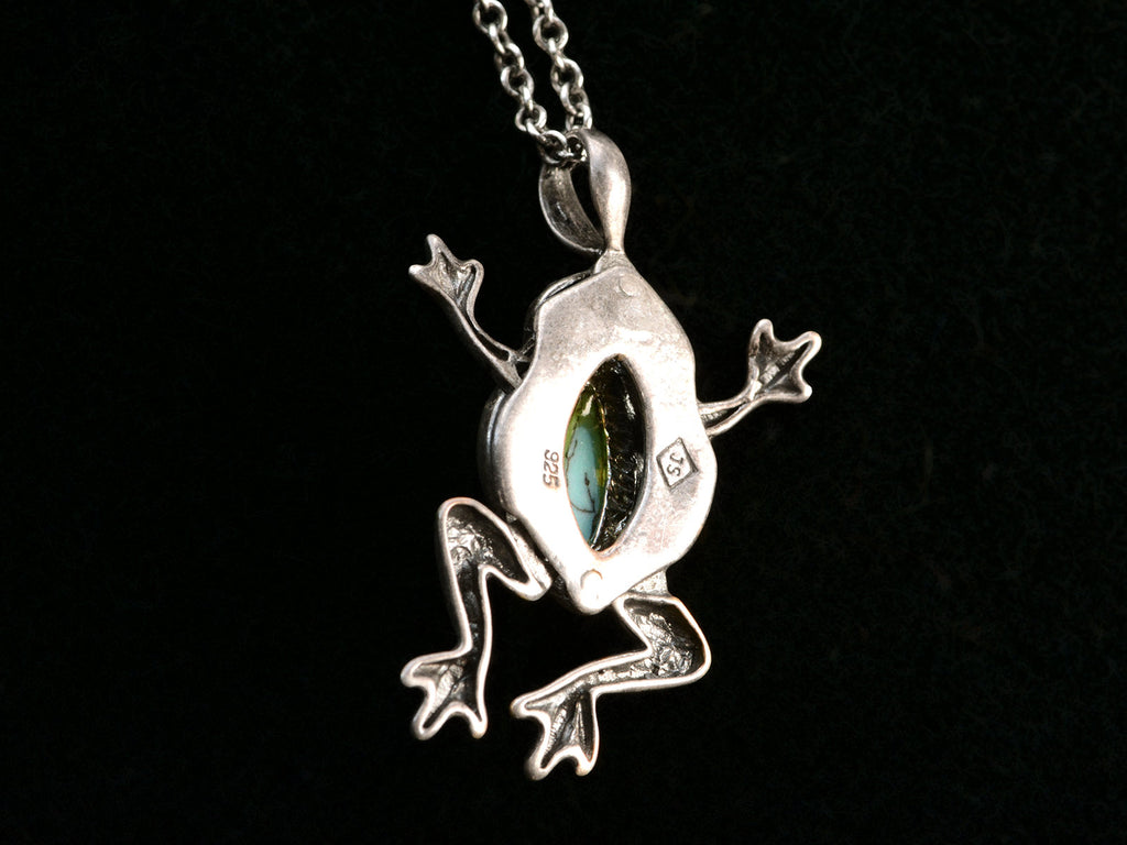 Reverse side of silver frog pendant with turquoise stone on a black background. Stamps visible "925" and "JS"