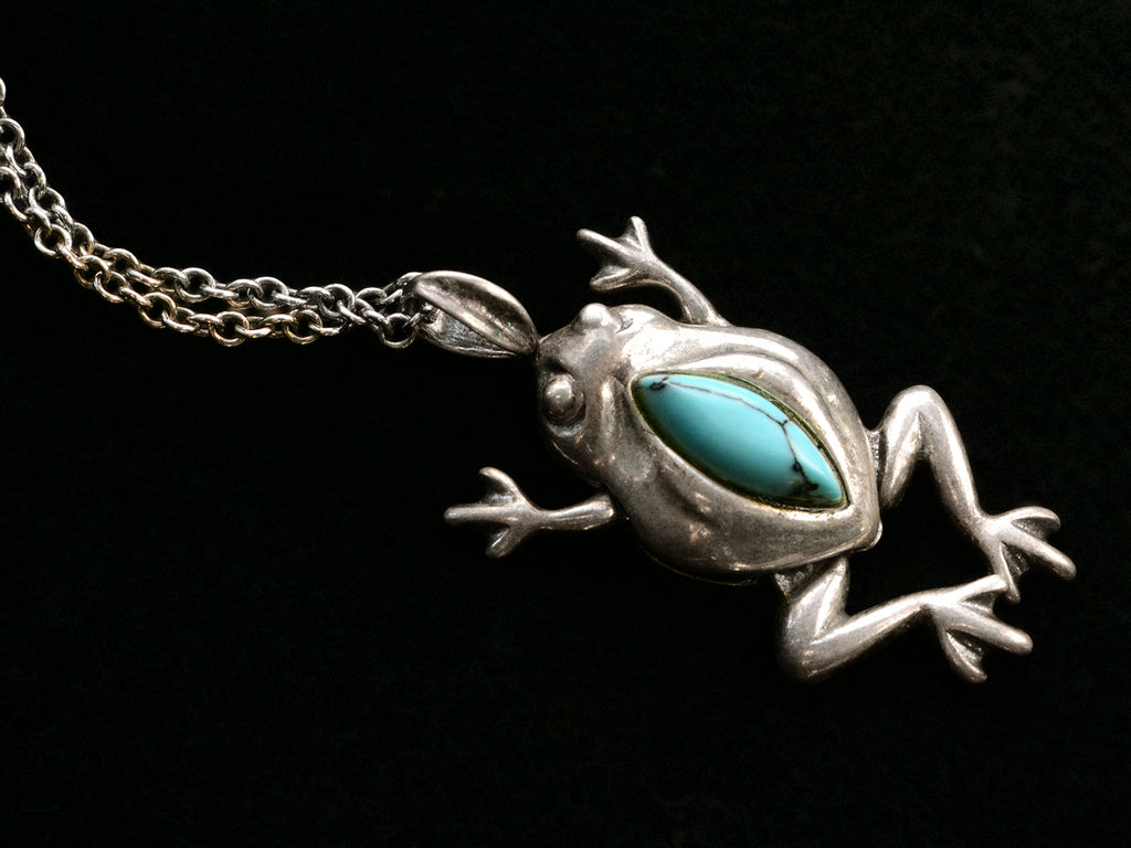 Silver frog pendant with turquoise stone on a black background