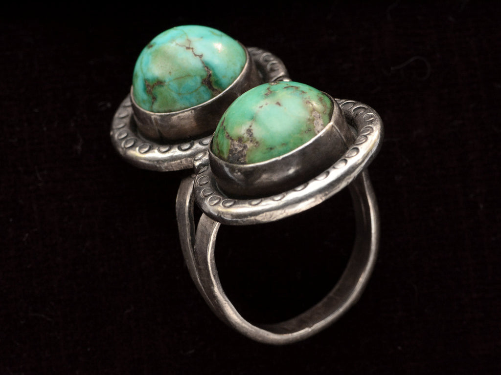 Angled side view of Silver ring with two turquoise stones on a black background

