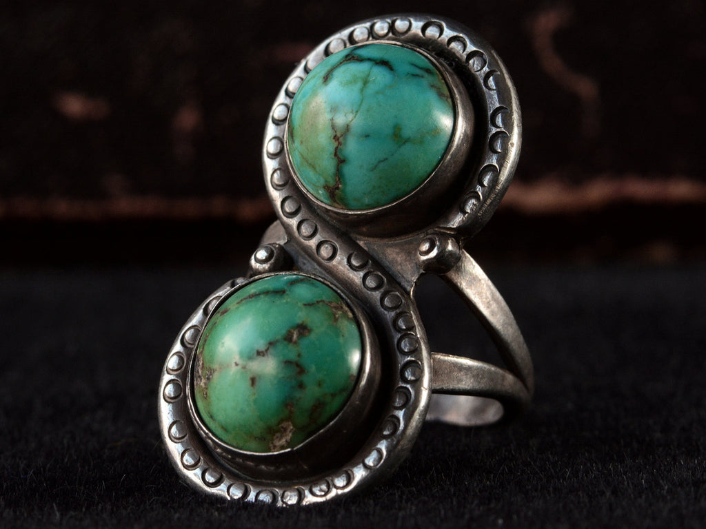 Right angled front view of Silver ring with two turquoise stones on a black background

