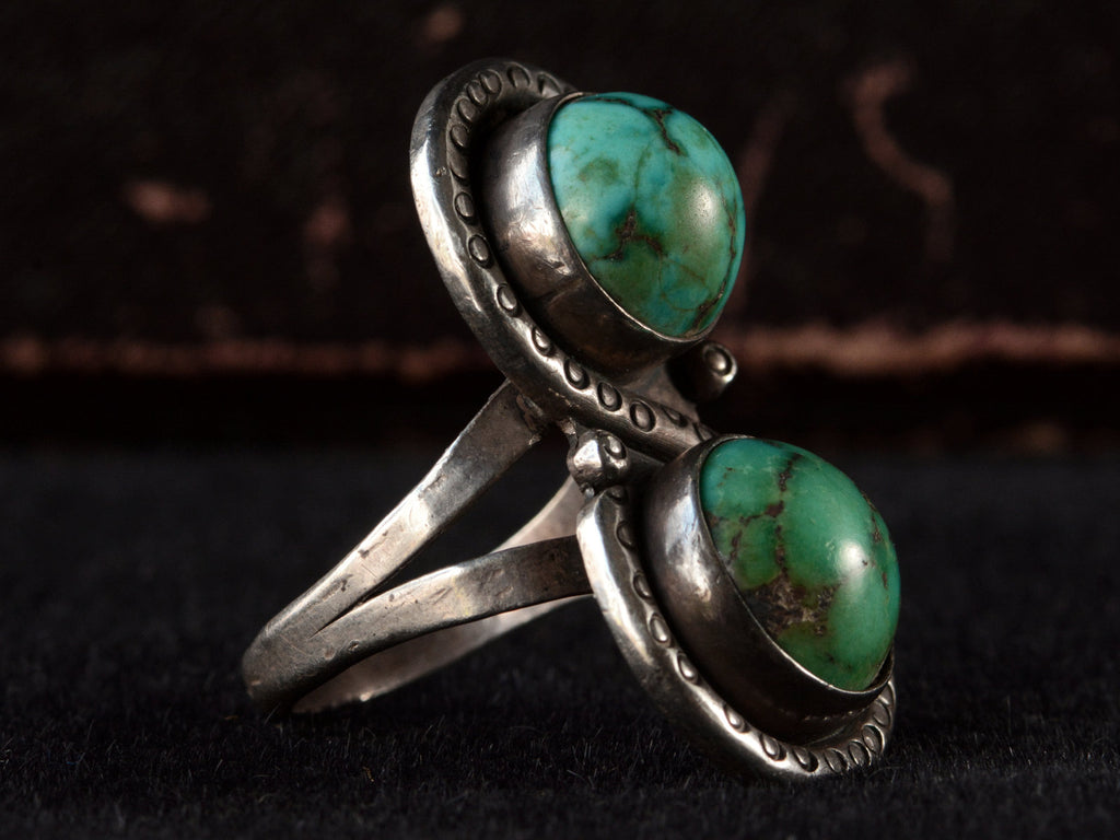 Left angled side view of Silver ring with two turquoise stones on a black background


