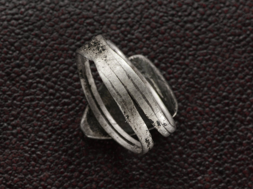 Back of shank view of a sterling silver ring featuring set against a dark textured background.